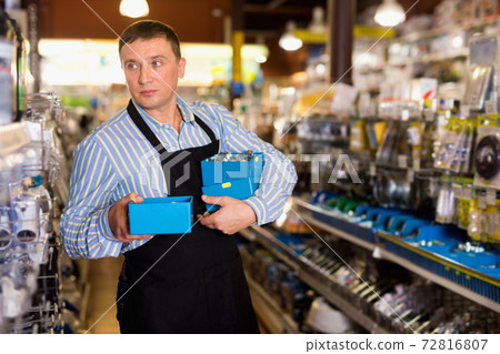 Man standing near the counter and selling tools in hardware shop 72816807