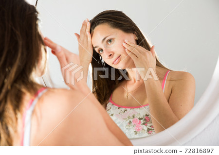 Adult woman using mirror in bedroom in morning Adult woman using mirror in bedroom in morning 72816897
