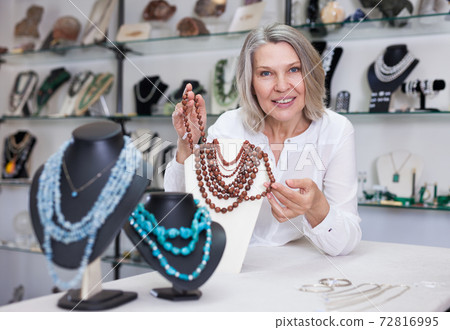 Female seller demonstrates golden stone necklace Female seller demonstrates golden stone necklace 72816995