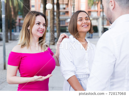Young women are talking with stranger man who was meet Young women are talking with stranger man who was meet 72817068