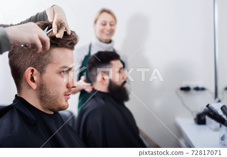 Young clients having their hair cut by hairdressers 72817071