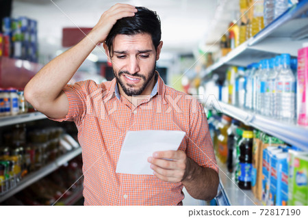 Adult male customer is looking in note in supermarket Adult male customer is looking in note in supermarket 72817190