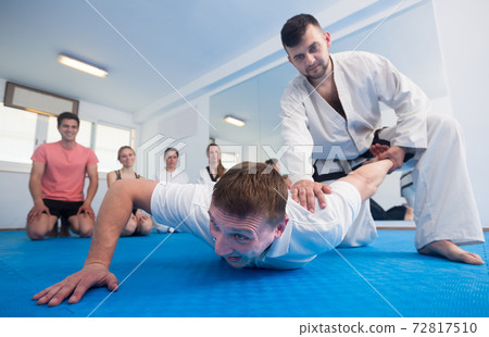 man training new taekwondo holds with adults during class man training new taekwondo holds with adults during class 72817510