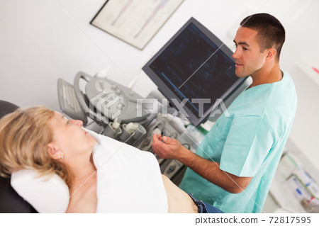 Man sonographer examining female patient Man sonographer examining female patient 72817595