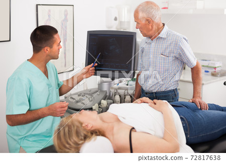 Adult man doctor talking with man and his wife Adult man doctor talking with man and his wife 72817638