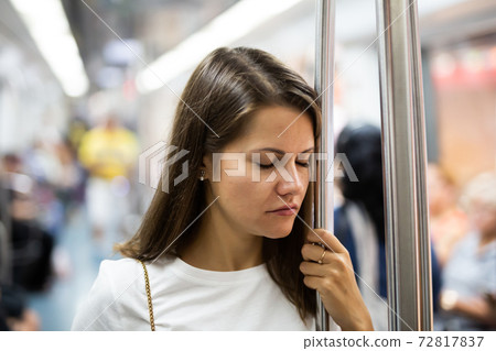 Woman sleeps standing in subway car 72817837