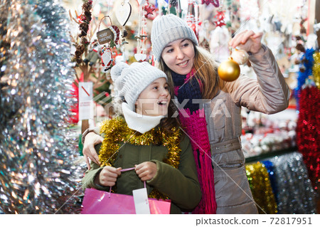 Woman and her daughter are preparing for Christmas and choosing balls on the tree Woman and her daughter are preparing for Christmas and choosing balls on the tree 72817951