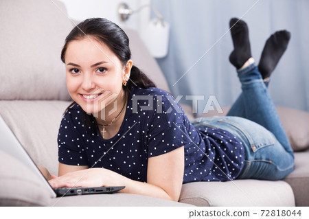 Woman lying on sofa with laptop Woman lying on sofa with laptop 72818044