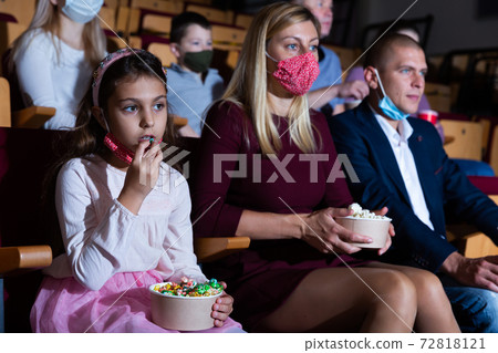 Family with child eating popcorn and watching a movie in cinema Family with child eating popcorn and watching a movie in cinema 72818121