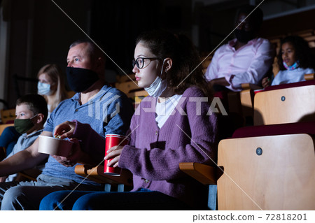 Father with his teenage daughter eating popcorn and watching a movie in cinema Father with his teenage daughter eating popcorn and watching a movie in cinema 72818201