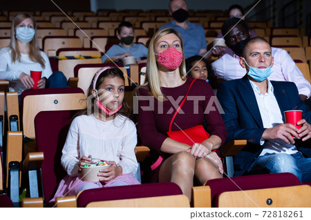 mother, father and their children sitting at film in auditorium during epidemic 72818261