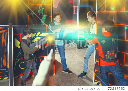 Group of happy teenagers with laser guns having fun on dark lase 72818262