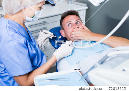 Young man frightened by dentist Young man frightened by dentist 72818325
