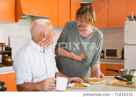 Aged woman offering breakfast to husband 72818336