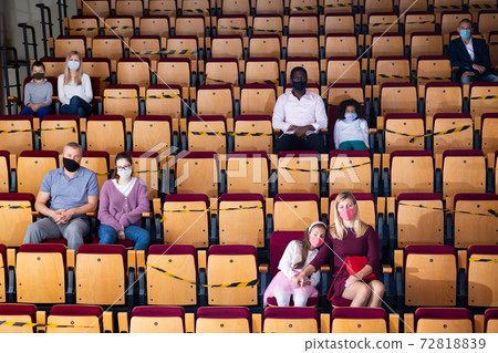 Spectators in protective masks sit in the theater hall observing social distance 72818839