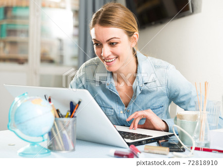 Smiling girl sitting at table at home calculating domestic finances and bills Smiling girl sitting at table at home calculating domestic finances and bills 72818910