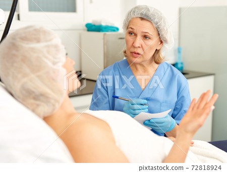 Skillful cosmetologist consulting young woman in medical esthetic office Skillful cosmetologist consulting young woman in medical esthetic office 72818924