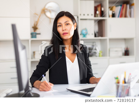 Adult business woman using laptop at workplace 72819137
