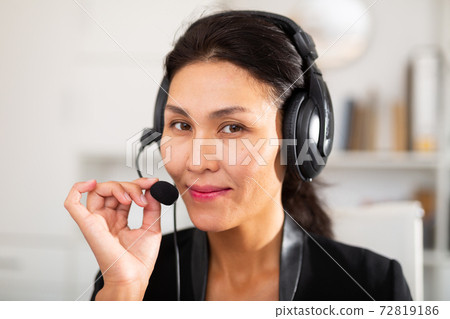 Office worker woman is working at a computer and talking by headset with client in office 72819186