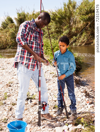 Man and boy holding fish on rod Man and boy holding fish on rod 72819476