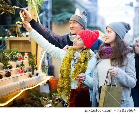 friendly family couple with teen girl choosing Christmas decoration 72819664