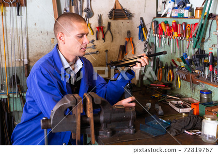 Skilled craftsman of weapons workshop repairing of small-bore handgun 72819767
