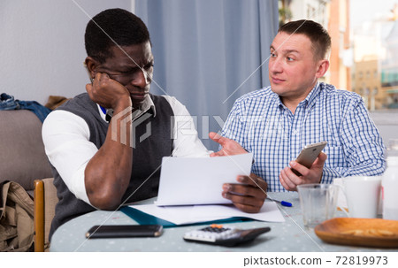 Two troubled friends with phone and papers at home Two troubled friends with phone and papers at home 72819973