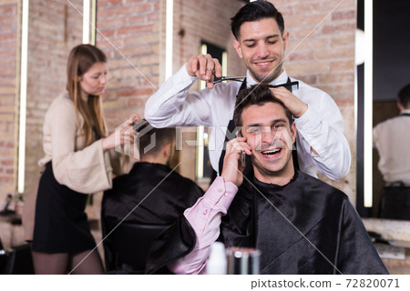 Cheerful man talking on phone in barbershop 72820071