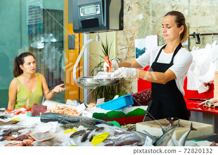 Smiling female weighing raw prawns on scales Smiling female weighing raw prawns on scales 72820132