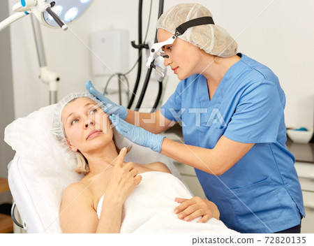 Doctor is examining mature woman patient before the procedure Doctor is examining mature woman patient before the procedure 72820135
