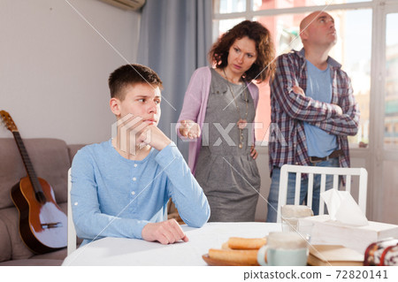 Upset teenage boy scolded by mother and father 72820141