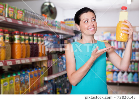 Happy female in supermarket buying juice in bottle Happy female in supermarket buying juice in bottle 72820143