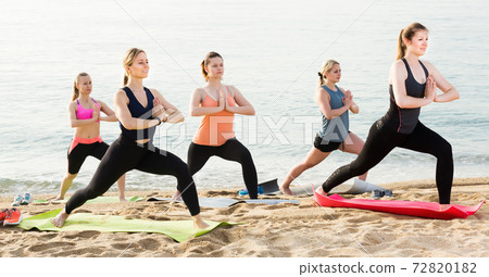 Women practicing yoga position on sandy beach Women practicing yoga position on sandy beach 72820182