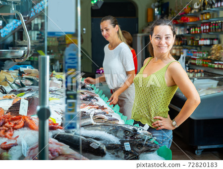 Satisfied female customer standing near seafood Satisfied female customer standing near seafood 72820183