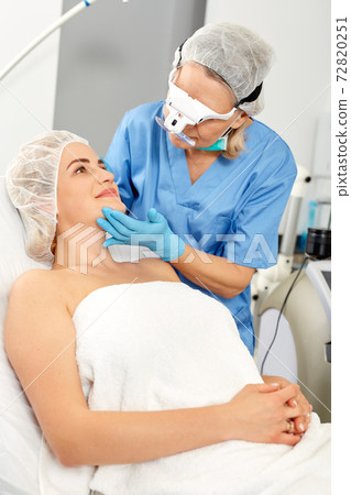 Professional cosmetician examining face skin of girl in clinic of esthetic cosmetology Professional cosmetician examining face skin of girl in clinic of esthetic cosmetology 72820251