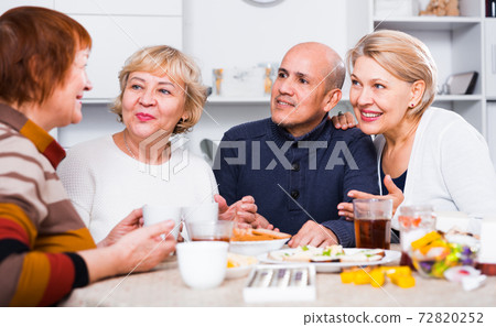 Mature women and their friend are drinking tea and talking Mature women and their friend are drinking tea and talking 72820252