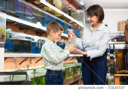 Boy and mother with fish in plastic bag Boy and mother with fish in plastic bag 72820507
