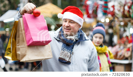 Smiling man in Santa hat with bags Smiling man in Santa hat with bags 72820630