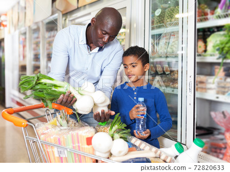 man with son choosing fresh greens and vegetables 72820633