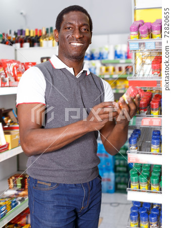 Portrait of smiling African man choosing spice in supermarket Portrait of smiling African man choosing spice in supermarket 72820655