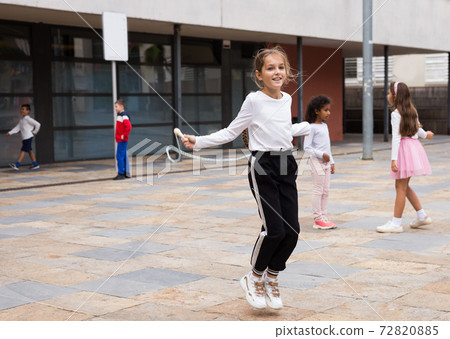 Schoolgirl jumping game by rubber band, kids friends on background 72820885