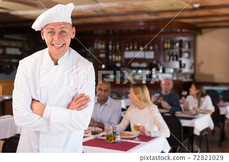 Portrait of chef with crossed arms in restaurant hall 72821029