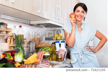 Portrait of cheerful woman with apple on the kitchen at home. Portrait of cheerful woman with apple on the kitchen at home. 72821105