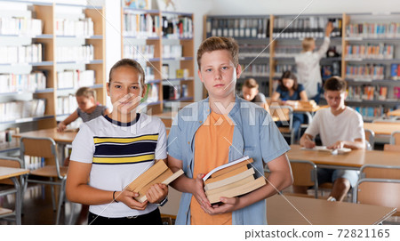 Boy and girl holding books in library Boy and girl holding books in library 72821165