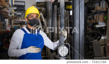 Foreman drives forklift in protective mask at the warehouse of hardware store Foreman drives forklift in protective mask at the warehouse of hardware store 72821166