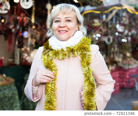 Positive female in tinsel on Christmas fair Positive female in tinsel on Christmas fair 72821386