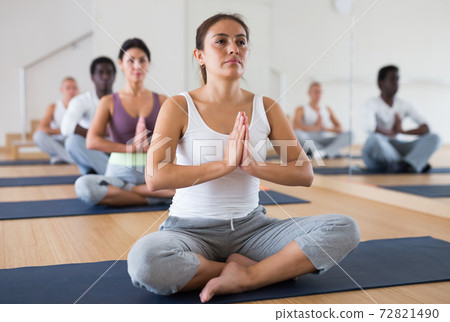 Young woman meditating at group yoga class Young woman meditating at group yoga class 72821490