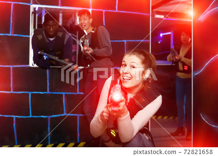 Adult girl aiming laser gun during lasertag game Adult girl aiming laser gun during lasertag game 72821658
