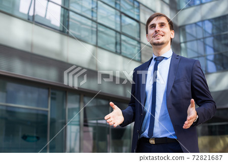 Smiling businessman standing outdoors Smiling businessman standing outdoors 72821687