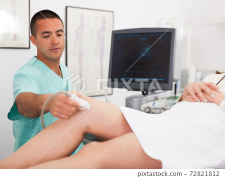 Man sonographer examining female patient 72821812